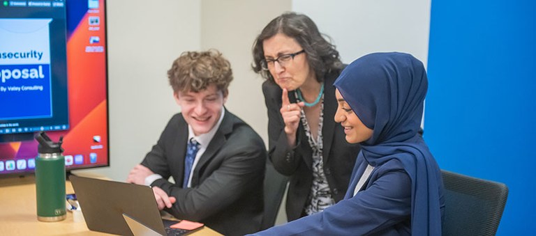 Braden Ward sitting with two other people that are looking at a laptop.