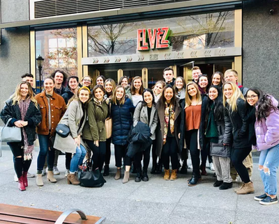 marketing students pose for a picture outside of a business on a trip for the prime club